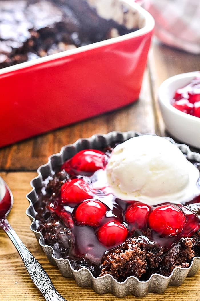 Chocolate pudding cake in dish with cherries and vanilla ice cream