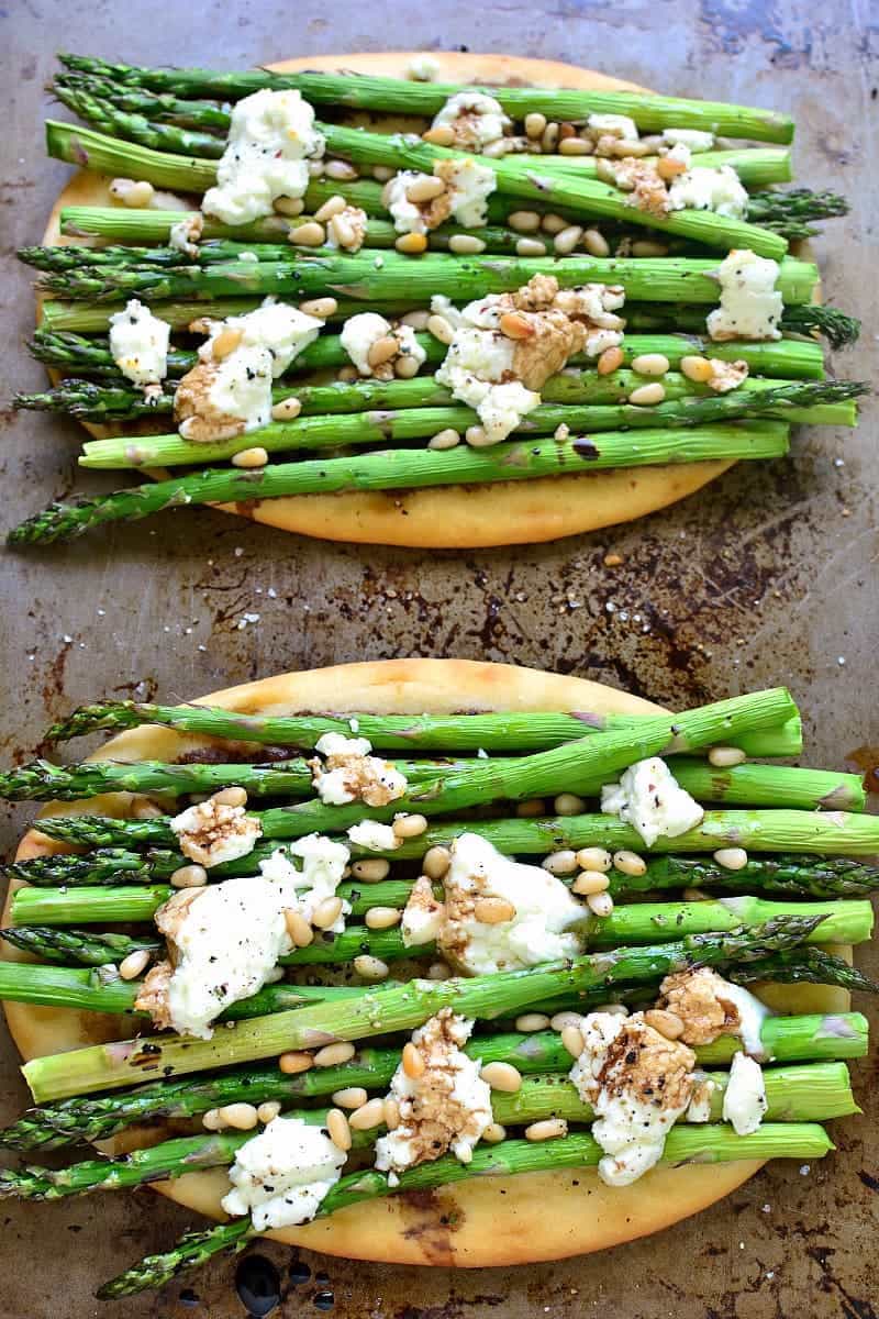 2 grilled flatbreads topped with goat cheese and stalks of fresh asparagus