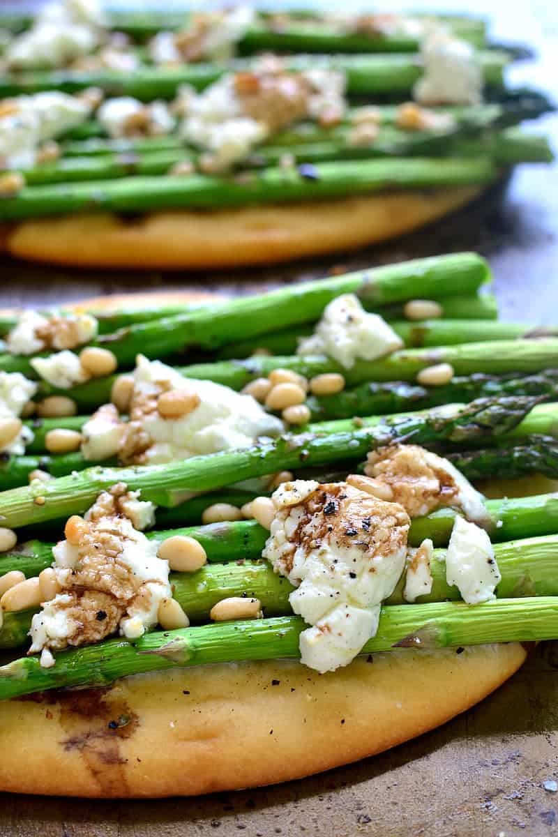 close up image of vegetarian flatbread topped with asparagus, goat cheese, and pine nuts