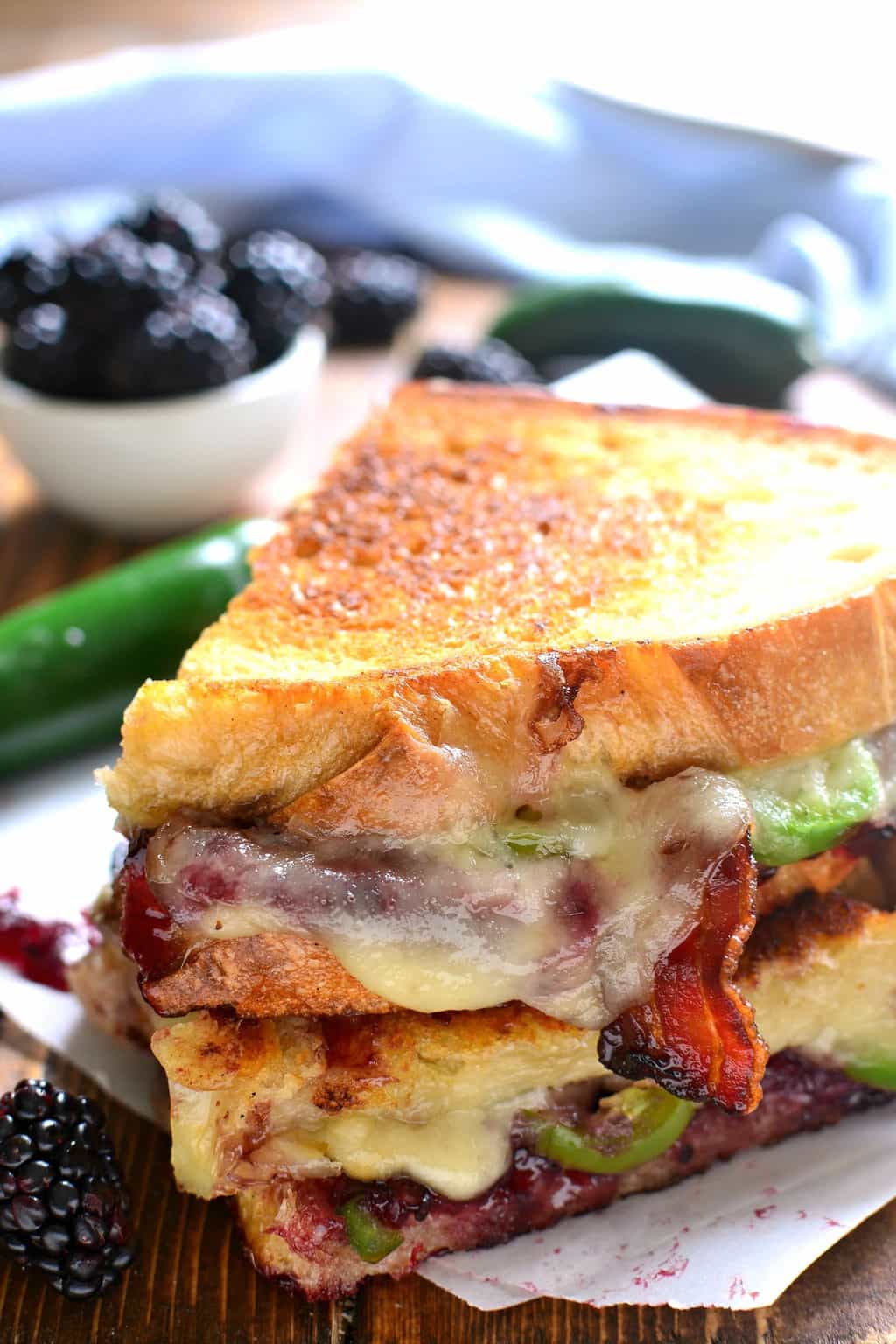 close up of melted cheese oozing down the side of a Blackberry Bacon Grilled Cheese sandwich