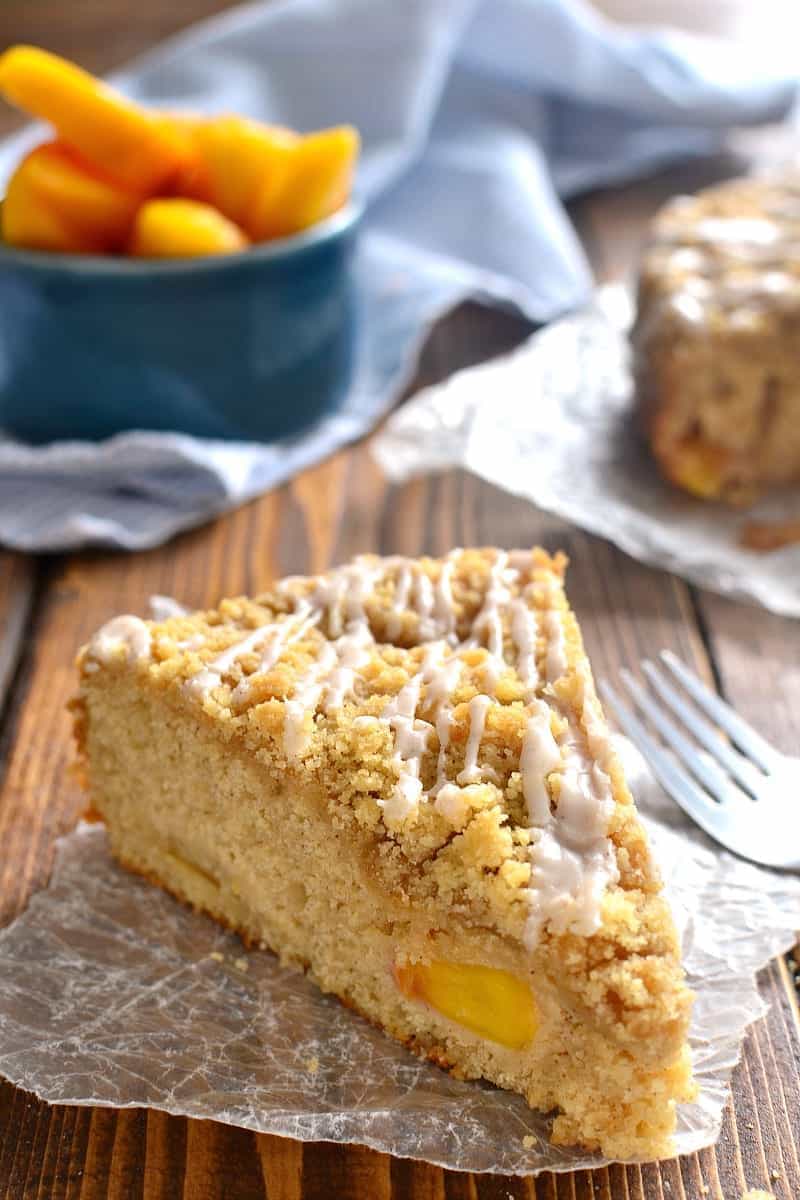a slice of homemade coffee cake made with fresh peaches, topped with cinnamon sugar drizzle