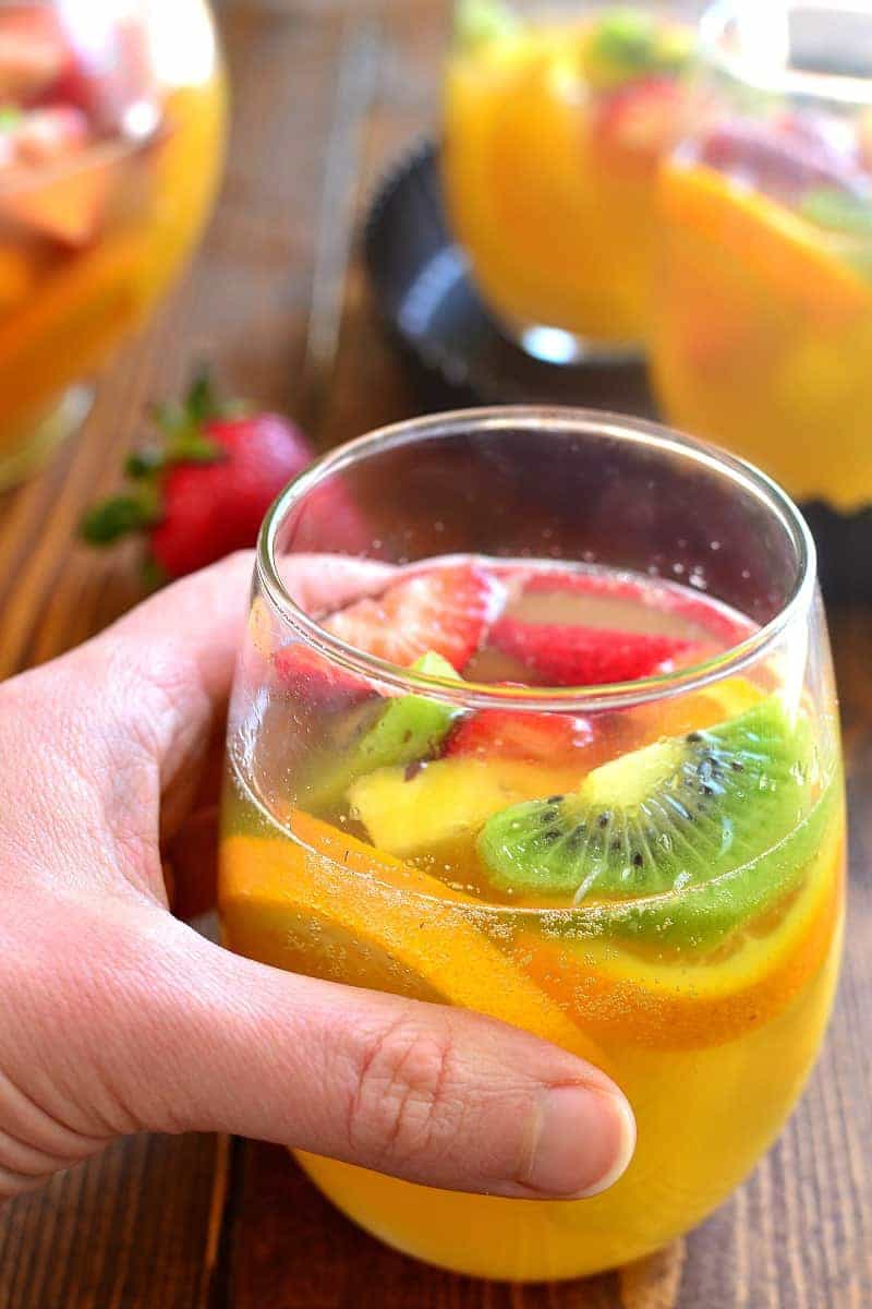 hand holding a glass of tropical fruit sangria