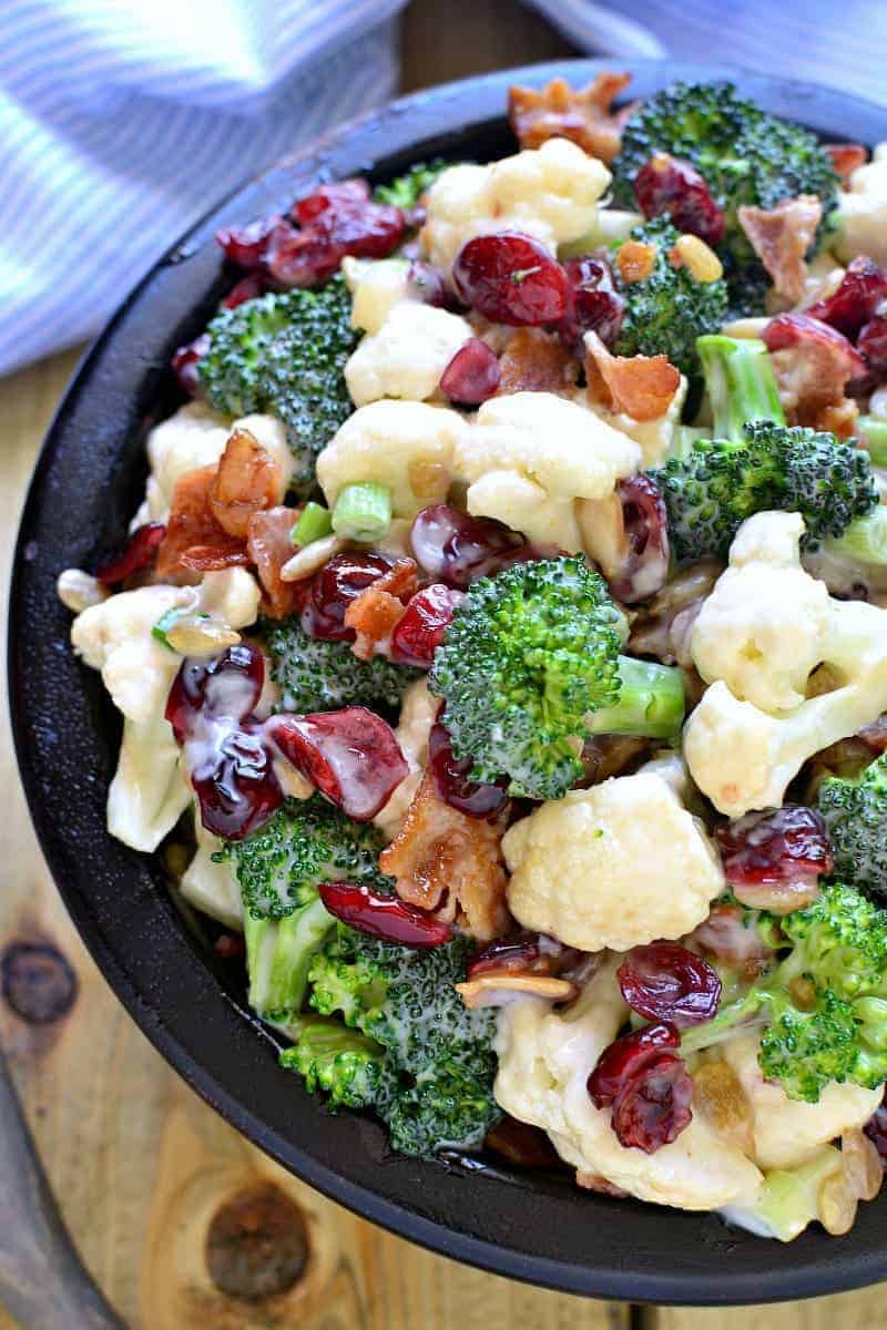 The BEST Broccoli Salad recipe - loaded with fresh broccoli, cauliflower, green onions, bacon, sunflower seeds, dried cranberries, and a lightened up honey mustard dressing. This salad is perfect for summer cookouts and picnics - a definite crowd pleaser!