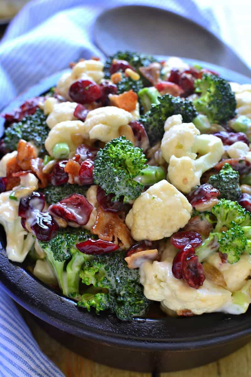 The BEST Broccoli Salad recipe - loaded with fresh broccoli, cauliflower, green onions, bacon, sunflower seeds, dried cranberries, and a lightened up honey mustard dressing. This salad is perfect for summer cookouts and picnics - a definite crowd pleaser!