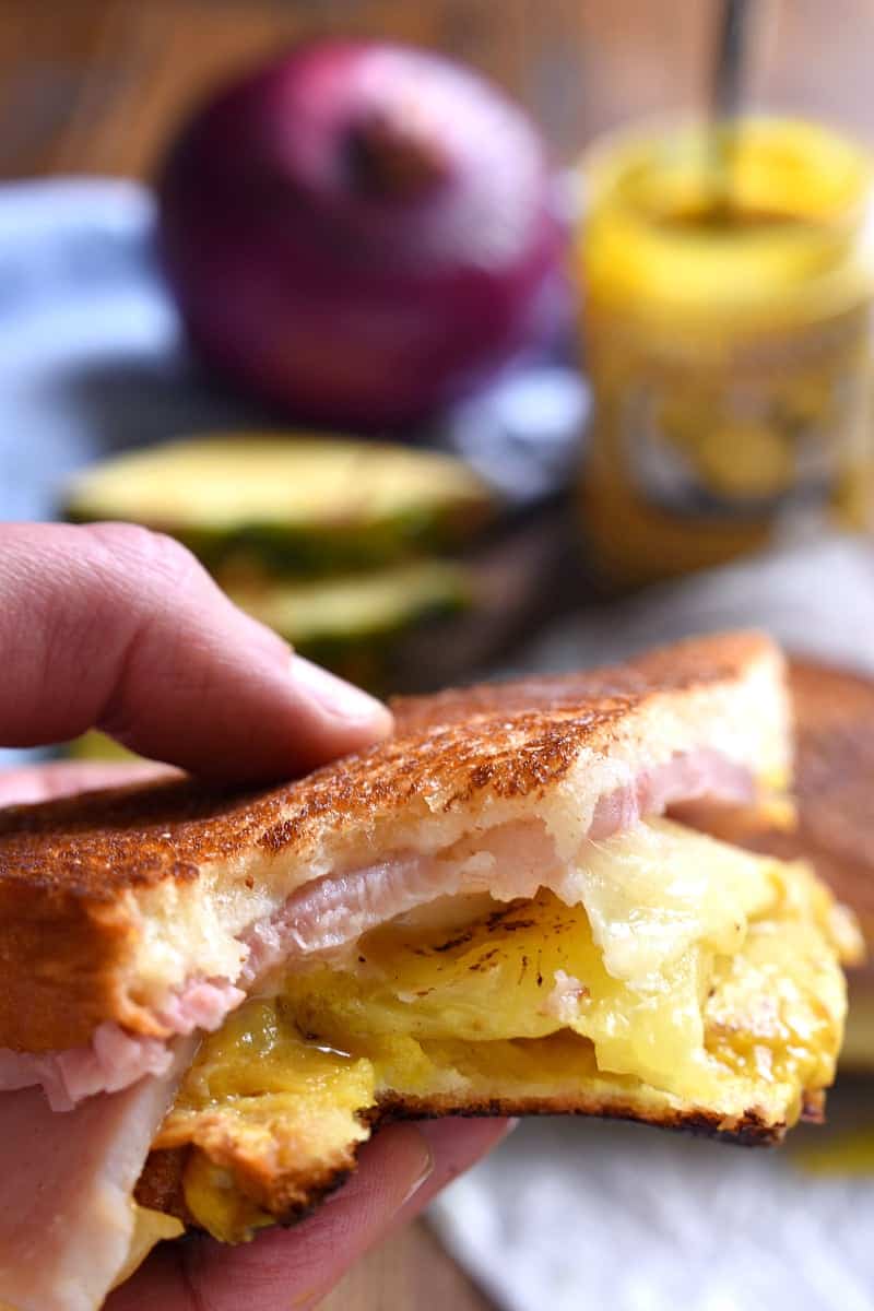 hand holding a Hawaiian ham grilled cheese sandwich with a bite taken out of it