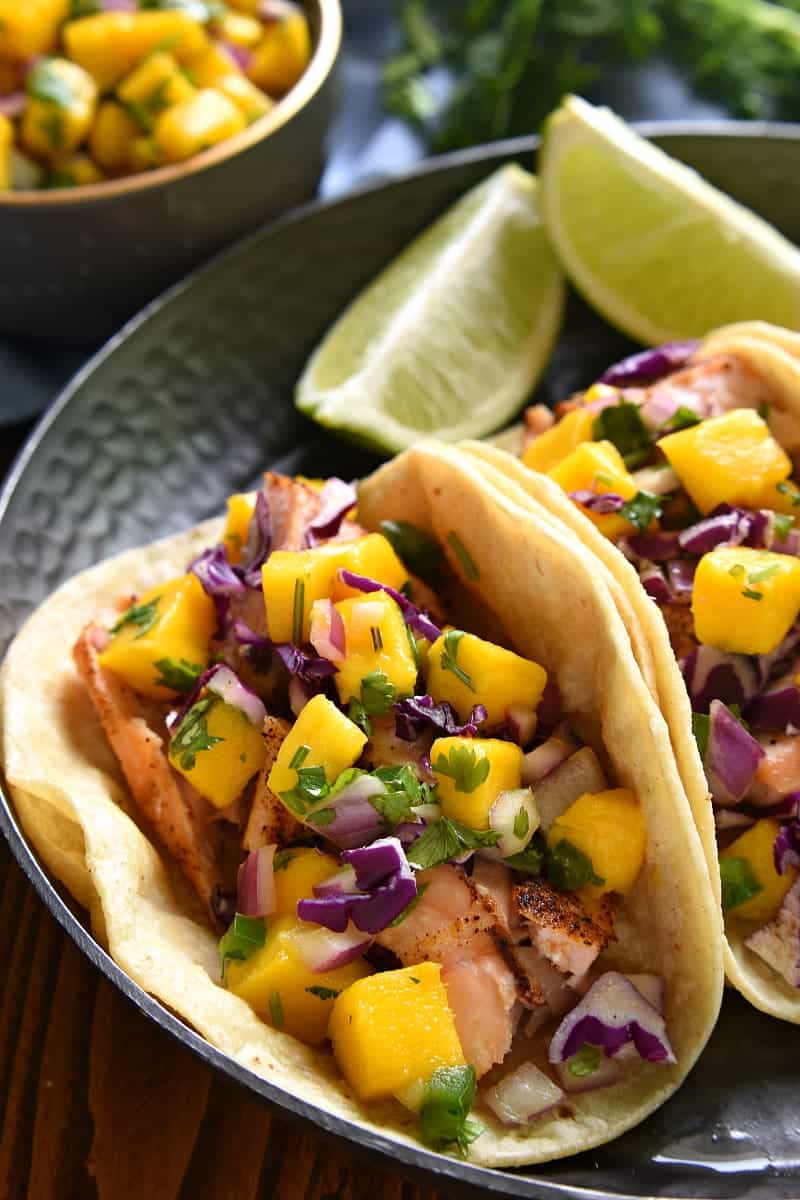 plate of salmon fish tacos topped with fresh mango salsa