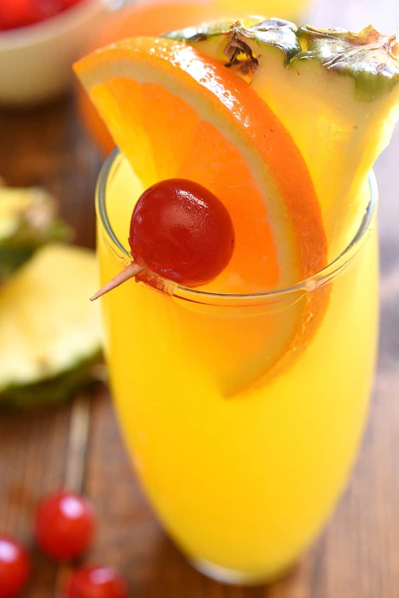 overhead image of a tropical mimosa cocktail garnished with a skewer of tropical fruit