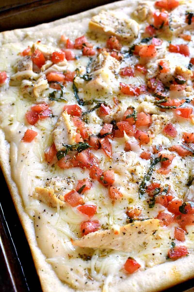 This Bruschetta Chicken Alfredo Pizza is a little taste of Italy, right in your own kitchen! Packed with delicious flavor and ready in under 30 minutes, this pizza is perfect for family night, date night, or a fun night with friends!