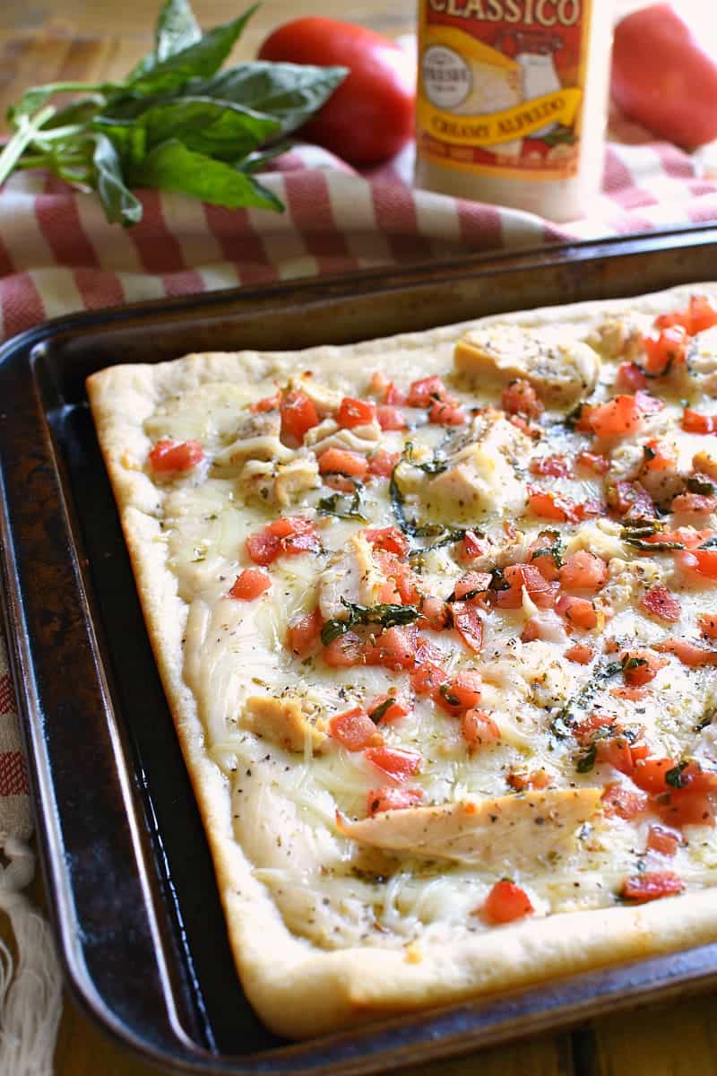 This Bruschetta Chicken Alfredo Pizza is a little taste of Italy, right in your own kitchen! Packed with delicious flavor and ready in under 30 minutes, this pizza is perfect for family night, date night, or a fun night with friends!