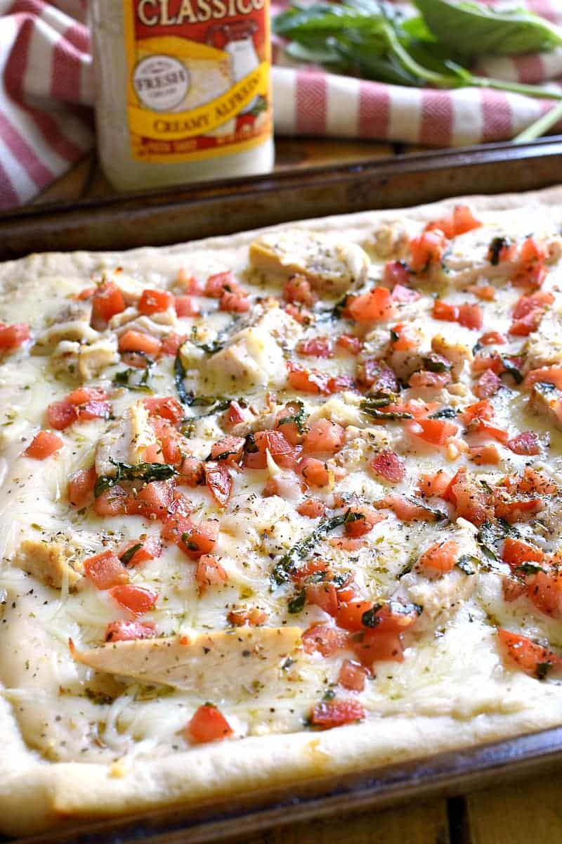 This Bruschetta Chicken Alfredo Pizza is a little taste of Italy, right in your own kitchen! Packed with delicious flavor and ready in under 30 minutes, this pizza is perfect for family night, date night, or a fun night with friends!