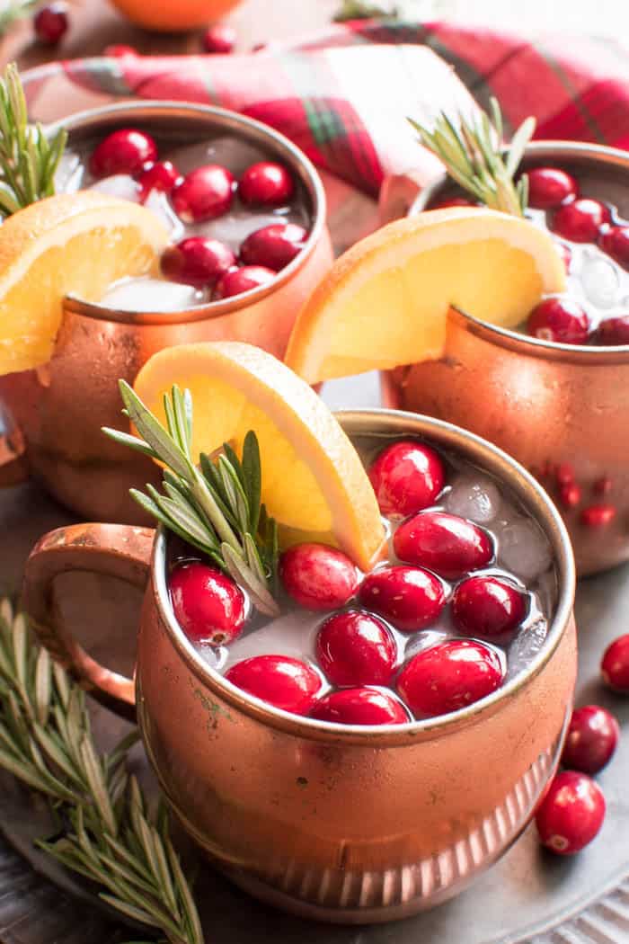 If you love Moscow Mules, these Holiday Cranberry Mules are sure to be a hit! Loaded with the delicious flavors of cranberry, orange, and ginger, and garnished with a sprig of fresh rosemary, these Mules are the perfect cocktails for your holiday season. And they're not only delicious, but beautiful, too! Which makes them an obvious addition to your Thanksgiving, Christmas, and New Years Eve menu. Best of all, these drinks come together quickly with just a handful of simple ingredients....and they can be pre-mixed for easy entertaining. If you're looking for a new go-to beverage this holiday season, look no further. These Holiday Cranberry Mules are IT!
