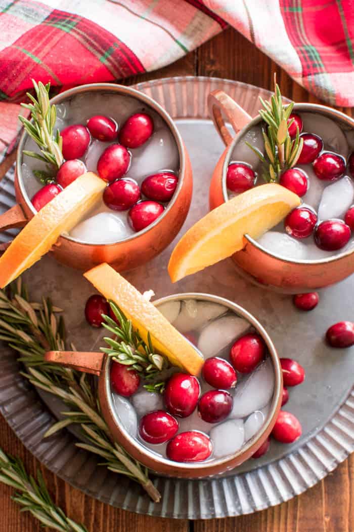 If you love Moscow Mules, these Holiday Cranberry Mules are sure to be a hit! Loaded with the delicious flavors of cranberry, orange, and ginger, and garnished with a sprig of fresh rosemary, these Mules are the perfect cocktails for your holiday season. And they're not only delicious, but beautiful, too! Which makes them an obvious addition to your Thanksgiving, Christmas, and New Years Eve menu. Best of all, these drinks come together quickly with just a handful of simple ingredients....and they can be pre-mixed for easy entertaining. If you're looking for a new go-to beverage this holiday season, look no further. These Holiday Cranberry Mules are IT!