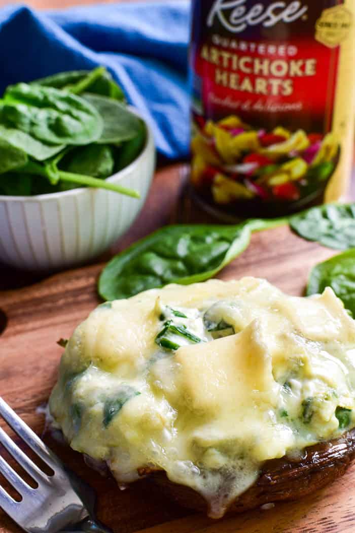 These Spinach Artichoke Stuffed Portobellos make a delicious appetizer, side dish, or meatless main dish. Loaded with a creamy blend of fresh spinach, artichoke hearts, sour cream, cheeses, and seasonings, these portobello mushroom caps are topped with brie cheese and baked to gooey perfection.