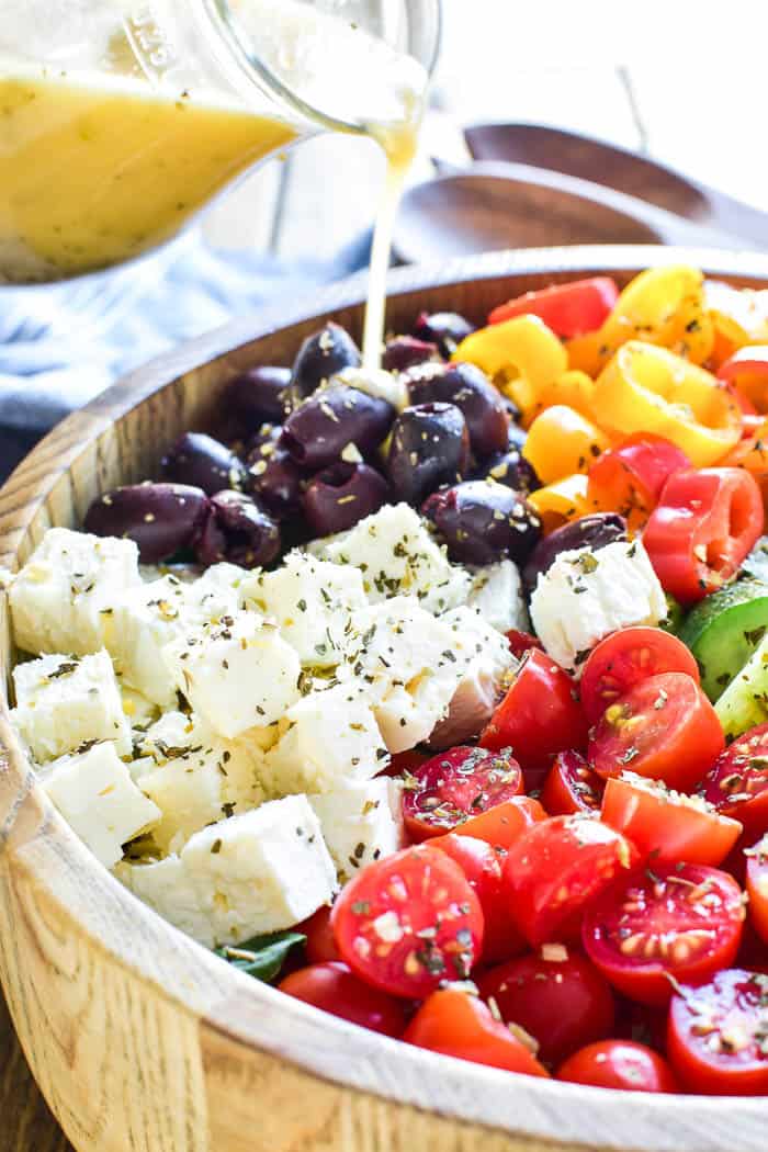 Greek Dressing pouring over salad in serving bowl