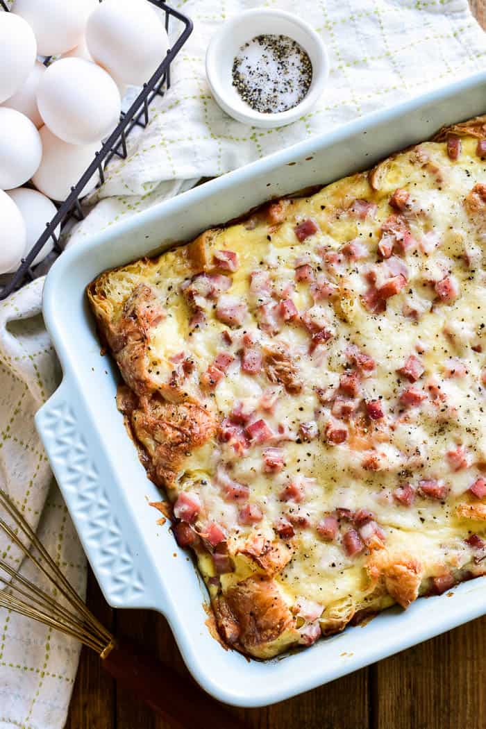Overhead image of Ham & Cheese Croissant Egg Bake with a basket of eggs