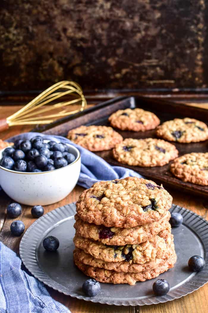Stack of Blueberry Oatmeal Cookies on a serving tray with a bowl of blueberries in the background