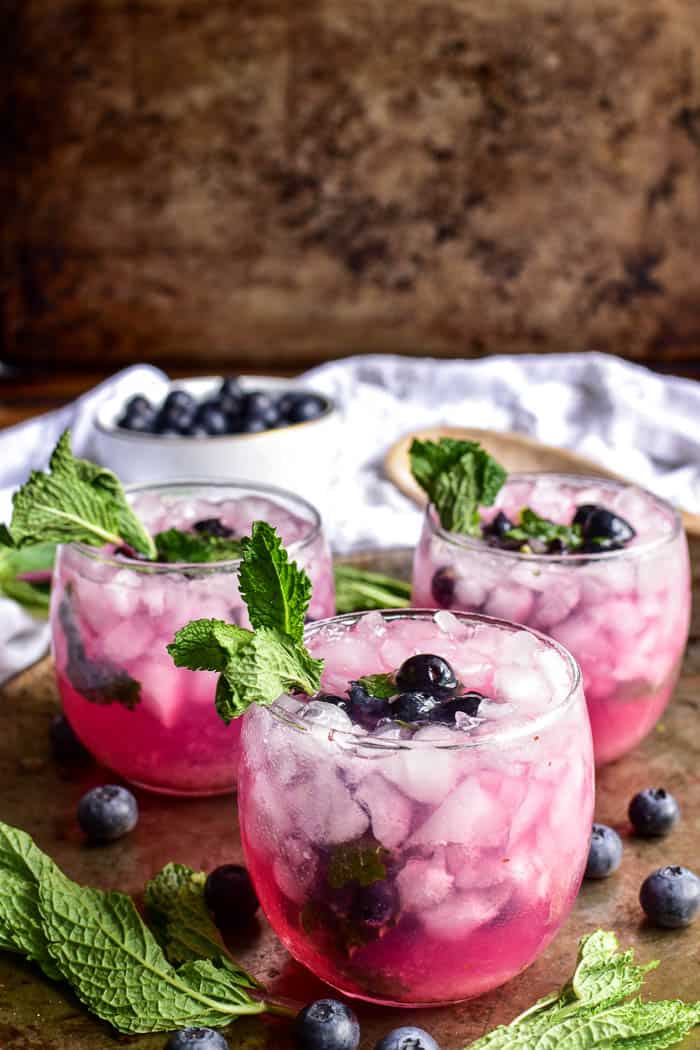 Blueberry Mojitos on a serving tray with fresh blueberries and fresh mint