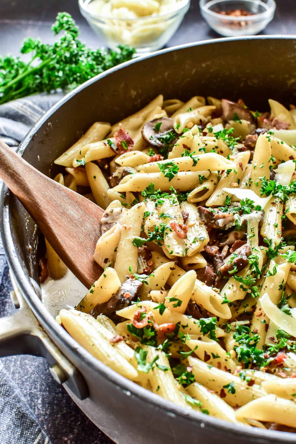 Close up of Penne with Mushrooms & Bacon with serving spoon in pan