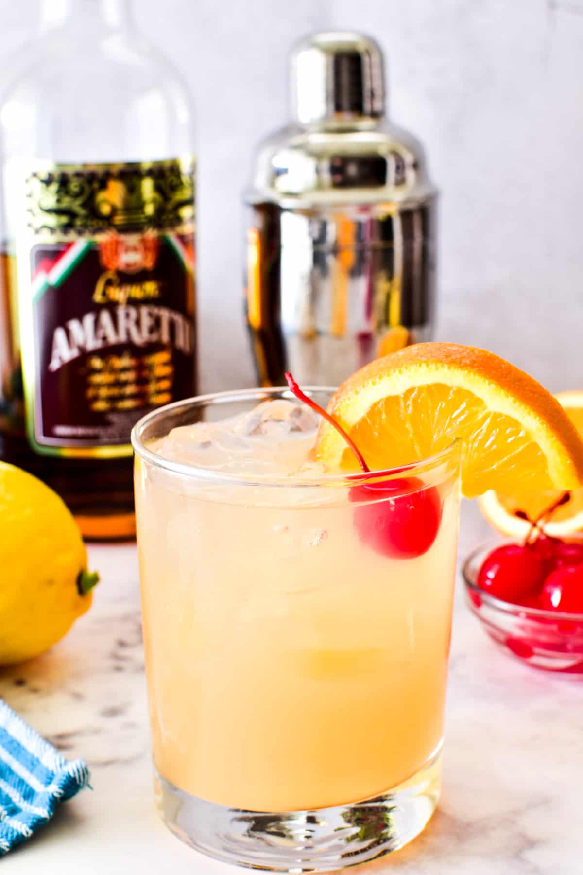 Amaretto Sour in a glass with an orange slice and maraschino cherry