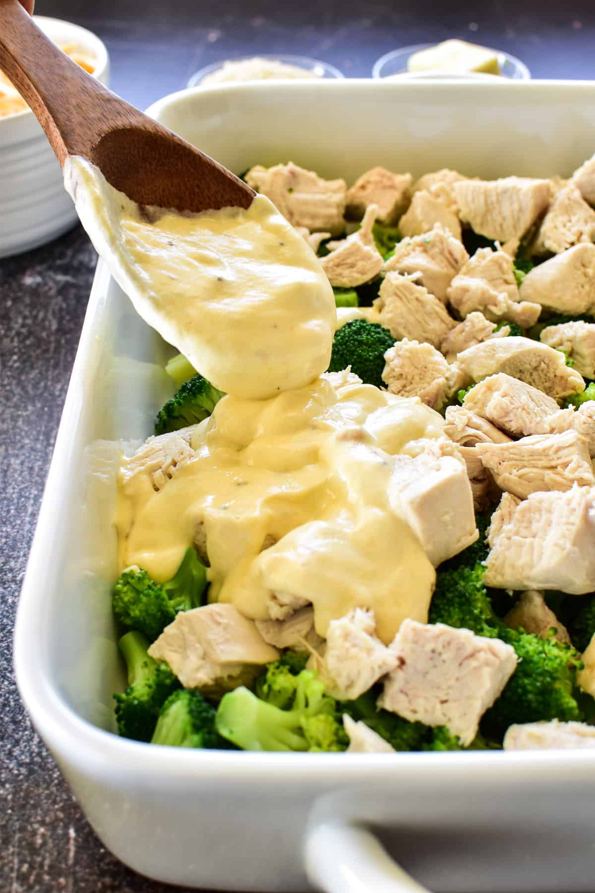 Photo of sauce layer being spooned onto chicken and broccoli